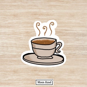 Puede incluir: Una taza de caf&eacute; blanca con un borde marr&oacute;n y caf&eacute; marr&oacute;n en su interior. La taza est&aacute; sobre un platillo blanco con vapor que sale del caf&eacute;. La imagen est&aacute; sobre un fondo de madera.