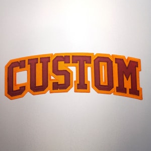 May include: A red and orange felt patch with the word "CUSTOM" in a bold, blocky font.