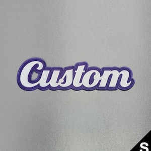 May include: A custom patch with the word "Custom" in white script lettering, outlined in purple. The patch is on a gray background. A black triangle with the letter "S" is in the bottom right corner.