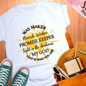 Könnte beinhalten: Weißes T-Shirt mit einem gelben Sonnen-Motiv und schwarzem Text, der "Way Maker Miracle Worker Promise Keeper Light in the darkness My God That is Who You Are" lautet.