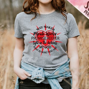 May include: Gray t-shirt with a red heart and black text that reads "Way Maker, Miracle Worker, Promise Keeper, Light in the darkness, My God, That is who you are."