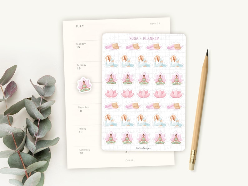 May include: A planner and stickers with yoga-themed illustrations. The planner is open to July, with a pencil resting beside it. The stickers feature yoga poses, lotus flowers, and yoga mats in pastel colors. The text "YOGA - PLANNER" is visible.