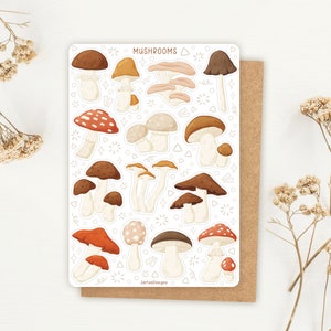 K&ouml;nnte beinhalten: Ein Bogen mit Aufklebern, die verschiedene Illustrationen von Pilzen in unterschiedlichen Farben und Stilen zeigen. Die Aufkleber sind wei&szlig; mit schwarzen Umrissen und in einem Raster angeordnet. Der Text "Mushrooms" befindet sich oben auf dem Bogen.