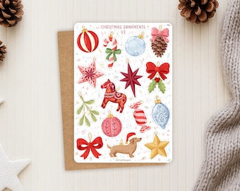 Puede incluir: Una hoja de pegatinas titulada CHRISTMAS ORNAMENTS V2 con ilustraciones de una bola a rayas rojas y blancas, bastón de caramelo, bola azul, piña, estrellas, lazo rojo, caballo Dala, muérdago, caramelo, bola rosa, perro salchicha y estrella dorada.