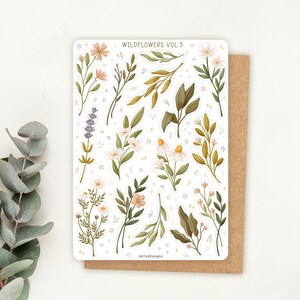 May include: A rectangular sticker sheet titled WILDFLOWERS VOL.3 featuring various botanical illustrations including lavender, daisies, and leafy branches in muted green, yellow, and pink tones, with small decorative sparkles and geometric shapes.