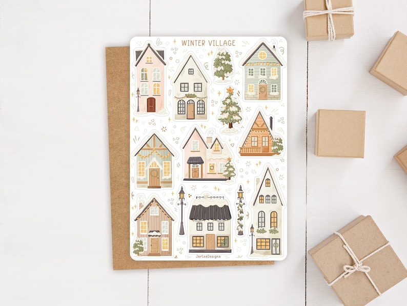 May include: A sticker sheet titled WINTER VILLAGE featuring various illustrated houses, evergreen trees, and street lamps in soft pastel and muted tones. The designs include A-frame cabins, multi-story buildings, and snowy roofs with warm glowing windows.