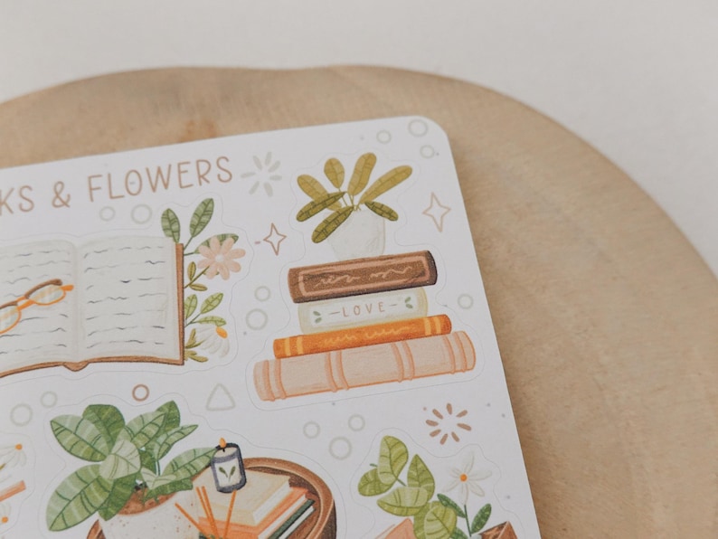 Peut inclure: Une planche d'autocollants illustrant des livres, des plantes en pot et des lunettes de lecture. Le texte "BOOKS & FLOWERS" est imprim&eacute; en haut. Les motifs incluent une pile de quatre livres, dont un marqu&eacute; "LOVE", et divers feuillages verts.