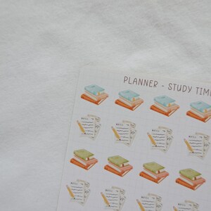May include: A sheet of planner stickers with watercolor illustrations. The stickers feature stacks of books in various colors and sheets of paper with pencils. The text "PLANNER - STUDY TIME" is at the top.