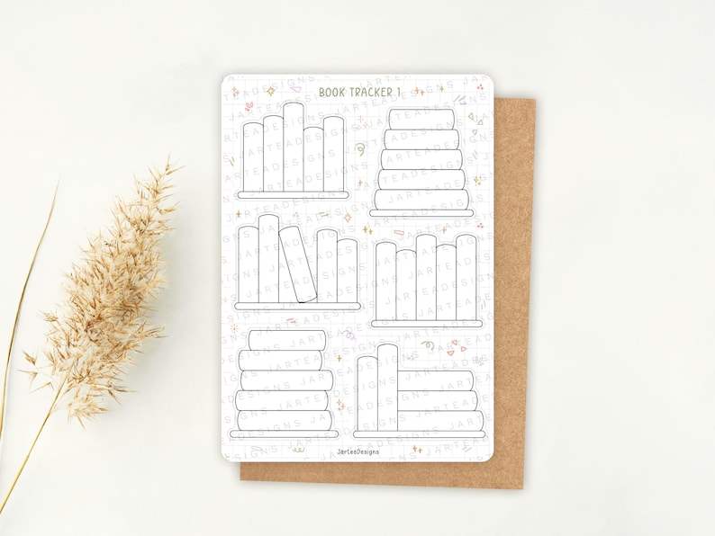 May include: A white sticker with the text "BOOK TRACKER 1" and illustrations of stacked books and bookshelves. The sticker is on a brown card, with a beige background and a dried plant in the corner.