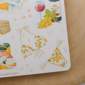 May include: A sheet of stickers featuring illustrations of summer and travel themes. Includes a bikini with a lemon pattern, a glass of red wine, a bottle of wine, grapes, and the Colosseum.