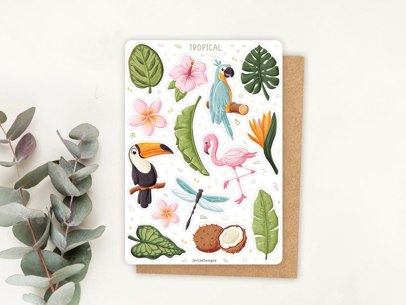 May include: A sticker sheet titled TROPICAL featuring illustrations of a blue parrot, a pink flamingo, a toucan, a dragonfly, a coconut, and various tropical flowers and green leaves. The sheet includes small decorative shapes and the text JerteeDesigns.