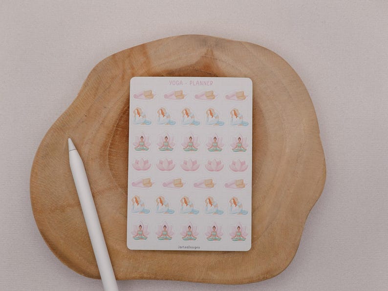 May include: A sheet of yoga planner stickers featuring various yoga poses in pastel colors. The stickers are on a white background with the text "YOGA + PLANNER". A white stylus pen rests on a wooden surface.