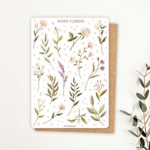 May include: A rectangular sticker sheet titled DAINTY FLOWERS featuring various watercolor-style illustrations of wildflowers, leaves, and sprigs in shades of green, pink, and purple, accented with small geometric shapes and stars.