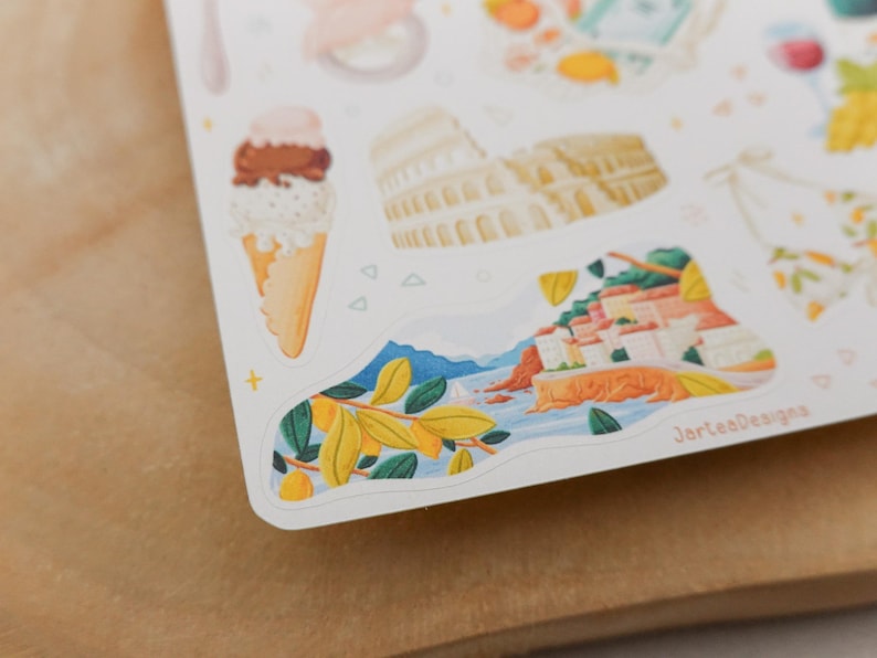 May include: A sheet of stickers featuring illustrations of Italian landmarks and food. The stickers include an ice cream cone, the Colosseum, and a coastal town scene. The stickers are in a watercolor style.