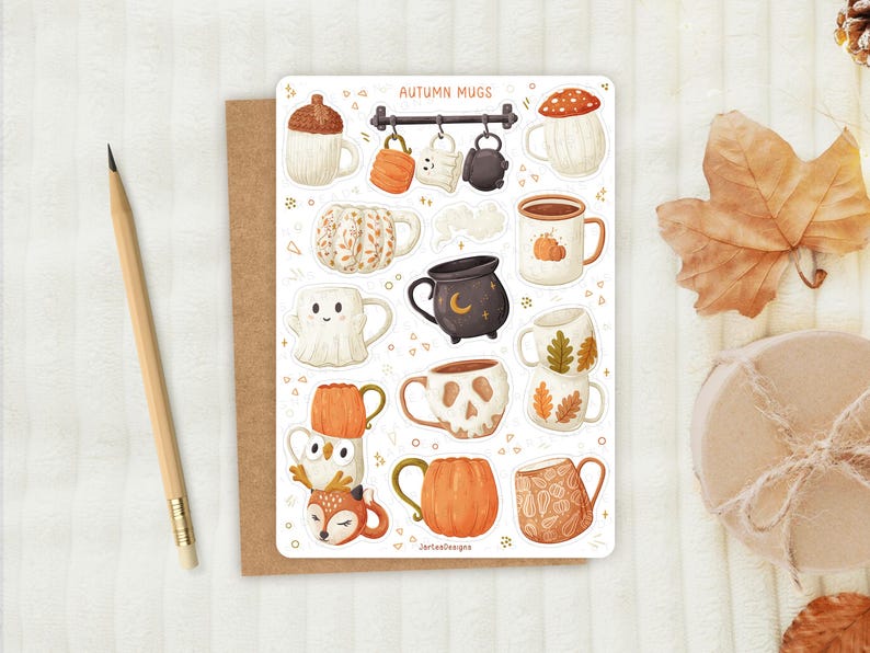 May include: A sticker sheet with illustrations of autumn mugs. Designs include a mushroom, pumpkin, ghost, and skull. The mugs are in shades of orange, brown, and white. The text "AUTUMN MUGS" is at the top. A pencil and a brown card are on the left.