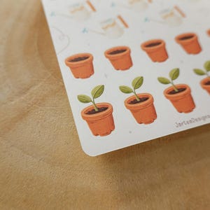 May include: A handmade wooden sign with the text "Welcome" in a handwritten style. The sign is painted white with a distressed finish, and a small green leaf is attached to the top. The sign is approximately 30 cm wide.