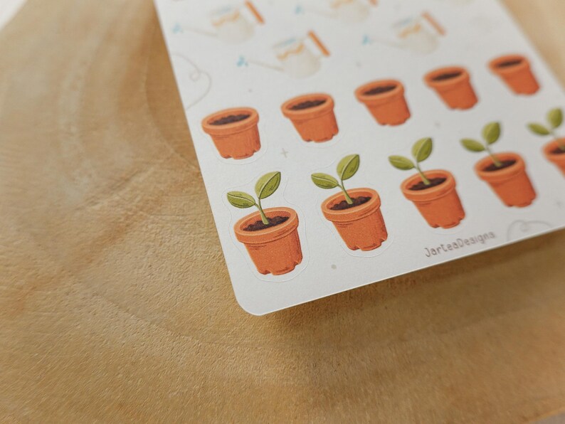 May include: A handmade wooden sign with the text "Welcome" in a handwritten style. The sign is painted white with a distressed finish, and a small green leaf is attached to the top. The sign is approximately 30 cm wide.