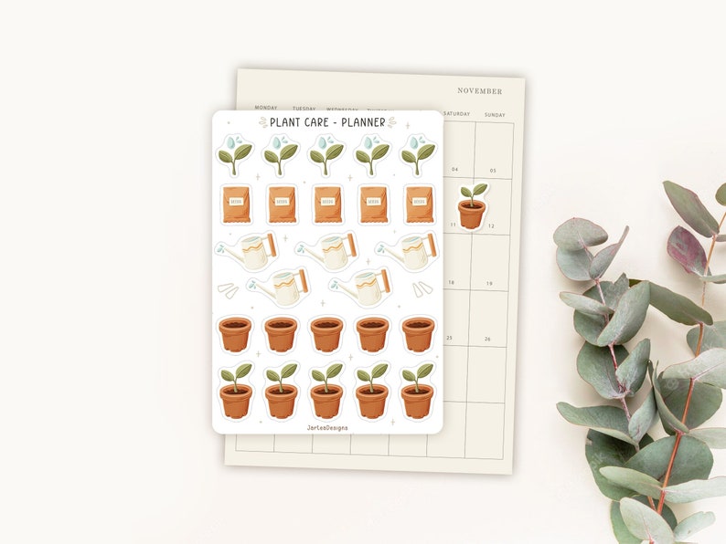 May include: A sticker sheet with a "Plant Care - Planner" theme, featuring illustrations of plants, seed packets, watering cans, and pots. A beige November calendar is in the background. The stickers are in shades of green, brown, and beige.