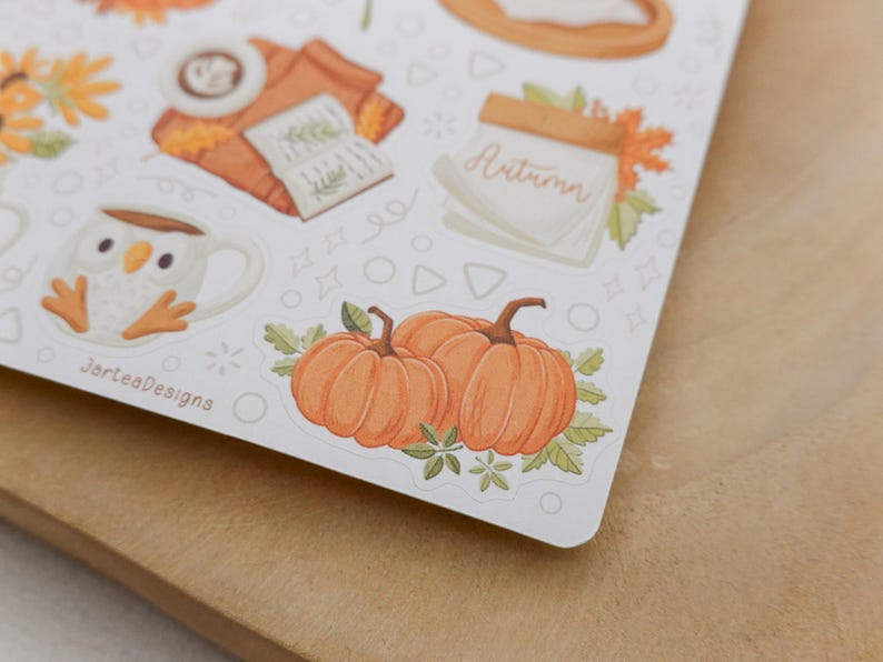 May include: A sheet of stickers featuring autumn-themed illustrations. The stickers include pumpkins, a mug with an owl design, a stack of books, and the word "Autumn". The stickers are on a white background.
