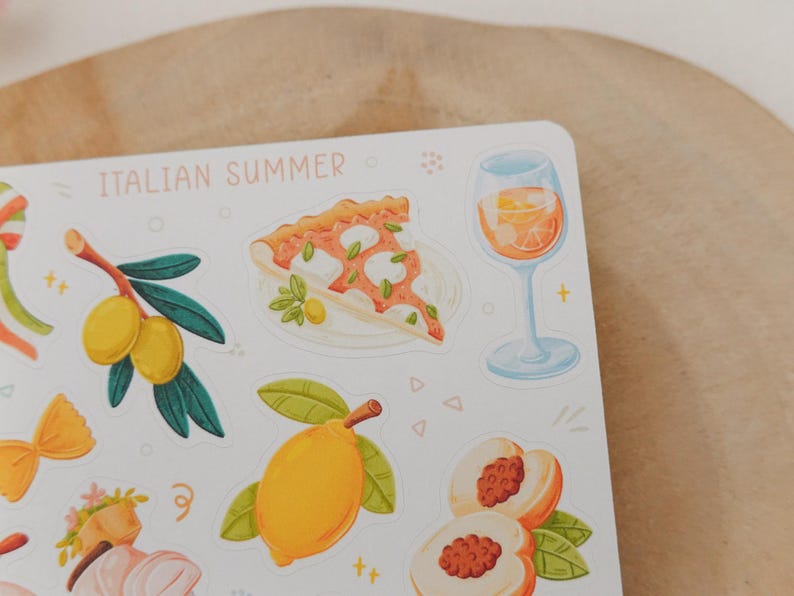 May include: A sticker sheet with illustrations of Italian summer elements. The sheet includes images of pizza, olives, lemons, peaches, and a glass of orange-colored beverage. The words "ITALIAN SUMMER" are printed at the top in light pink.