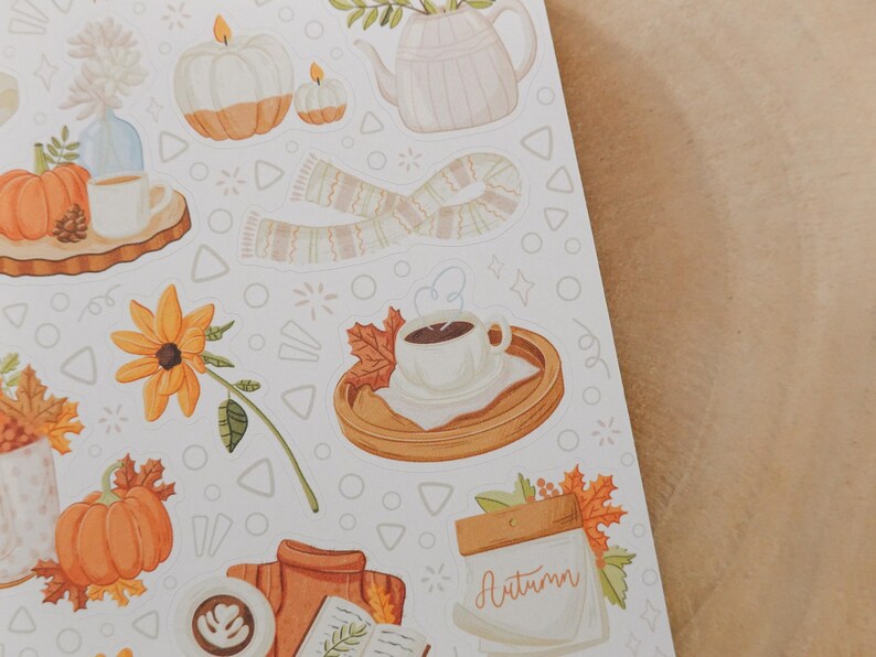 May include: A sheet of autumn-themed stickers featuring watercolor illustrations. The designs include pumpkins, candles, a scarf, a teapot, coffee cups, and fall foliage. The word "Autumn" is written on a calendar.