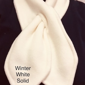 May include: A white fleece neck warmer with a knotted design. The text "Winter White Solid" is printed on the warmer.
