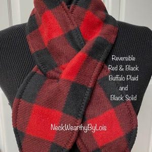 May include: Reversible red and black buffalo plaid and black solid fleece scarf. The scarf is displayed on a black mannequin. The text on the image reads: Reversible Red & Black Buffalo Plaid and Black Solid. The brand name is NeckWearyByLois.
