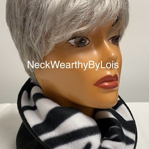 May include: Black and white zebra print fleece neck warmer. The neck warmer is folded over and has a black fleece lining. The text "NeckWearthyByLois" is visible on the image.