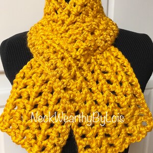 May include: A yellow crocheted neck warmer with a simple, elegant design. The neck warmer is made with a thick yarn and has a wide, comfortable fit.