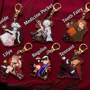Peut inclure: Six porte-cl&eacute;s en acrylique repr&eacute;sentant des personnages de style anime avec des anneaux dor&eacute;s. Les personnages incluent Isolda, Medicine Pocket, Tooth Fairy, Lilya, Regulus et Tennant. Chaque personnage est repr&eacute;sent&eacute; dans une pose et une tenue uniques, avec des couleurs vives et des motifs d&eacute;taill&eacute;s.