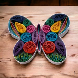 May include: A colorful butterfly made of rolled paper, with a white frame. The butterfly is made of different colors, including purple, blue, green, yellow, orange, and red.