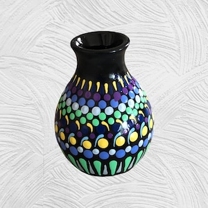 May include: A small black ceramic vase with a colorful dot pattern. The vase is decorated with green, blue, purple, and yellow dots.