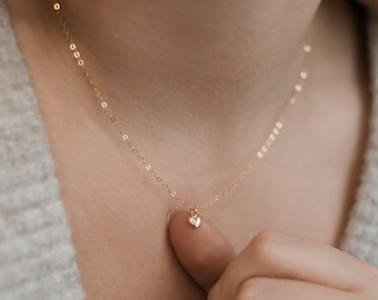 May include: A delicate gold chain necklace with a small, heart-shaped pendant.