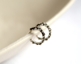May include: A pair of silver hoop earrings with a textured, slightly spiky design.