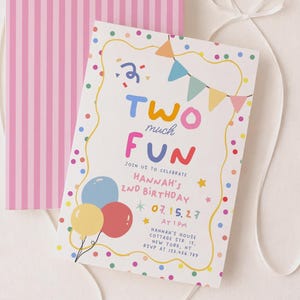 Op de afbeelding: Een verjaardagsuitnodigingskaart met kleurrijke stippen, ballonnen en vlaggetjes, met de tekst "TWO much FUN" en "HANNAH'S 2ND BIRTHDAY" en evenementdetails, gecombineerd met een roze en wit verticaal gestreepte envelop en wit lint.