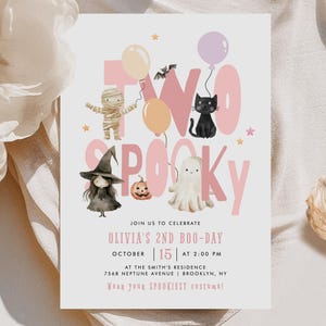 May include: A Halloween party invitation with the words "TWO SPOOKY" in pink. The invitation features illustrations of a mummy, a black cat, a witch, a ghost, a pumpkin, and balloons. The invitation also includes the text "Olivia's 2nd Boo-Day" and event details.