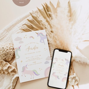 May include: A white invitation card with a unicorn theme. The card features a pink unicorn with a rainbow mane and tail, surrounded by clouds and stars. The text on the card reads "It's a magical day Amelia is turning five!" with the date and time of the event. The card is displayed on a white surface with a bouquet of dried pampas grass.