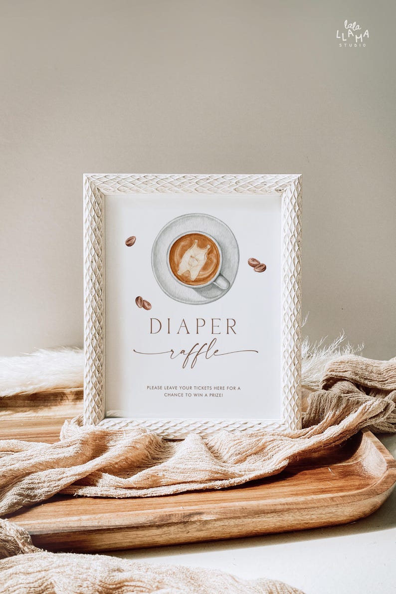 May include: A framed sign with a watercolor illustration of a coffee cup and beans. The sign reads "DIAPER raffle" with additional text below. The frame is white with a textured design. The sign is on a wooden tray with fabric.