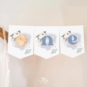 May include: A white banner with blue watercolor clouds and stars. The banner has three sections with the word "one" spelled out in blue letters. Each section features a rocket ship with a yellow moon in the first section.