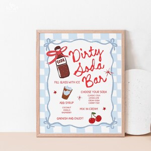 K&ouml;nnte beinhalten: Ein gerahmtes Schild mit einem hellen Holzrahmen zeigt einen blau-wei&szlig; karierten Hintergrund. Das Schild tr&auml;gt in roter Schrift die Aufschrift "Dirty Soda Bar" mit Anweisungen und Zutatenoptionen.