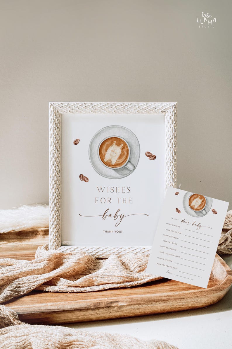 May include: A framed print with a coffee cup illustration and the text "Wishes for the baby". A matching card with a coffee cup illustration and fill-in-the-blank prompts is also present. Coffee beans are scattered around the frame.