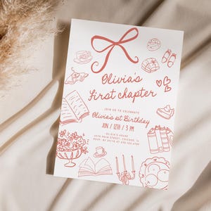 May include: A white invitation card with red illustrations and text. The card reads "Olivia's First Chapter" and includes drawings of books, desserts, and a bow. The invitation is for Olivia's 1st birthday.