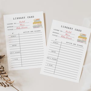 May include: Two white library cards with black text and a small stack of books illustration. The cards have lines for "Issued to," "Author," and "Title." The title on the cards reads "Baby Shower."