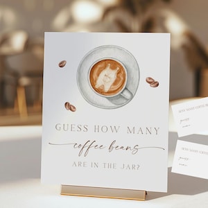 May include: A white sign with the text "GUESS HOW MANY coffee beans ARE IN THE JAR?" features a watercolor illustration of a coffee cup and scattered coffee beans. Two smaller cards are also visible.