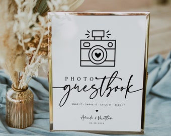 May include: A gold-framed sign with a black and white camera icon and the text "PHOTO guestbook" with the instructions "SNAP IT - SHAKE IT - STICK IT - SIGN IT". The sign also includes the names "Amanda & Matthew" and the date "08.20.20XX".