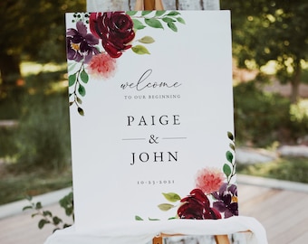 Könnte beinhalten: Ein Willkommens-Schild für eine Hochzeit mit einem Aquarell-Blumendesign in den Farben Burgunderrot, Rosa und Lila. Das Schild lautet "Willkommen zu unserem Anfang Paige & John 10.23.2021".