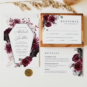 Pu&ograve; includere: Un set di inviti di nozze con un tema gotico. L'invito presenta un design floreale bordeaux e bianco con una silhouette di pipistrello nero. La carta di risposta presenta un design floreale simile e include una scadenza per la risposta del 21 agosto. Il testo sull'invito recita: "Til Death Do Us Part, Adelaide e Jonathan".
