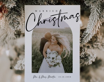 May include: A white card with a photo of a couple in a field. The text "MARRIED Christmas" is at the top of the card. The text "Mr. & Mrs. Martin 10.28.20XX" is at the bottom of the card.