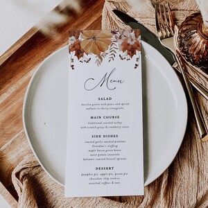 May include: A fall-themed menu with a watercolor illustration of pumpkins and leaves. The menu lists a salad, main course, side dishes, and dessert options. The text reads: "Edenwood Paperie, Menu, Salad, Mesclun greens with pears and spiced walnuts in sherry vinaigrette, Main Course, Traditional roasted turkey with scratch gravy & cranberry sauce, Side Dishes, Roasted garlic mashed potatoes, Grandma's stuffing, Maple bacon green beans, Sweet potato casserole, Balsamic roasted brussel sprouts, Dessert, Pumpkin pie, apple pie, pecan pie, Chocolate chip cookies, Assorted coffees & teas."
