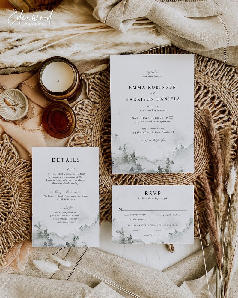 May include: Wedding invitation suite with a watercolor mountain landscape design. The invitation features the names Emma Robinson and Harrison Daniels, the wedding date, and the location. The RSVP card includes a section for guests to indicate their attendance and meal choices.